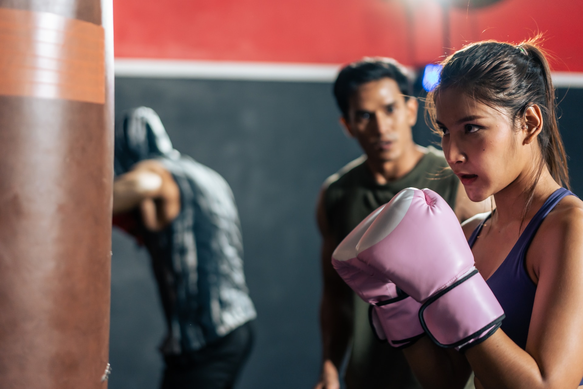 Une femme devant un sac de frappe en cours de boxe.