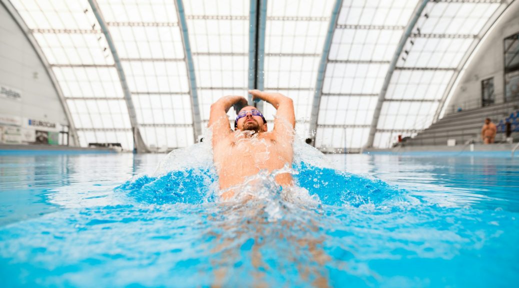 Un nageur s'entraîne en nage dos dans un bassin sportif.
