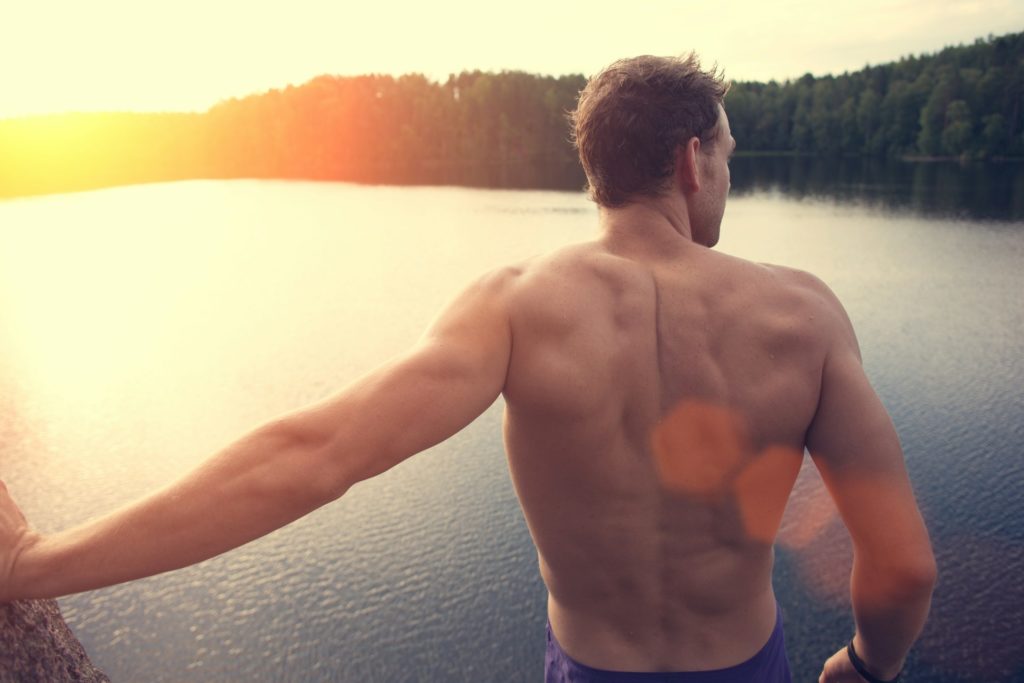Un sportif se tient torse nu un soir d'été sur un bateau.