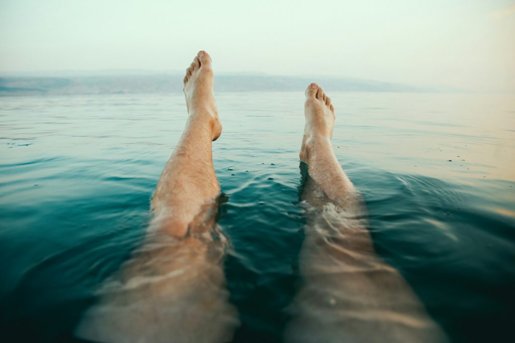Un homme dans l'eau, les jambes tendues.