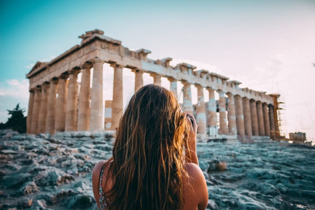 Une voyageuse prend en photo les vestiges d'un temple de Grèce antique.