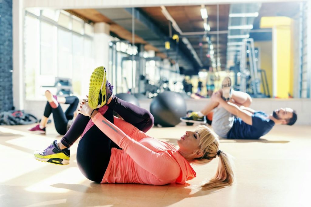 Un groupe de sportifs s'étirent les jambes dans un club de sport.