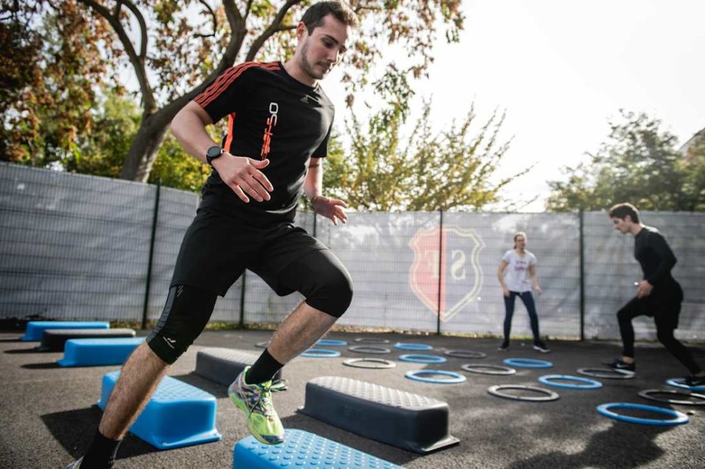 Un sportif en train de courir à côté de steppers de fitness à l'extérieur.