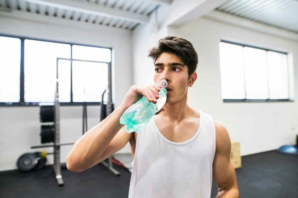 Une homme en train de boire dans un club de sport lumineux.