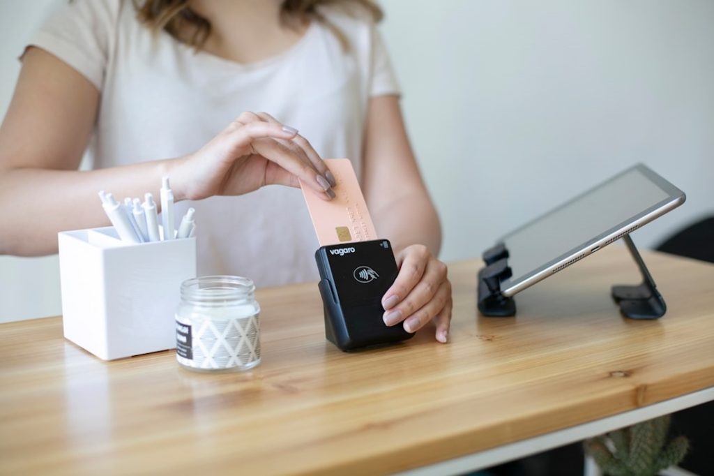 Une jeune femme est en train de payer avec un terminal de paiement par carte.