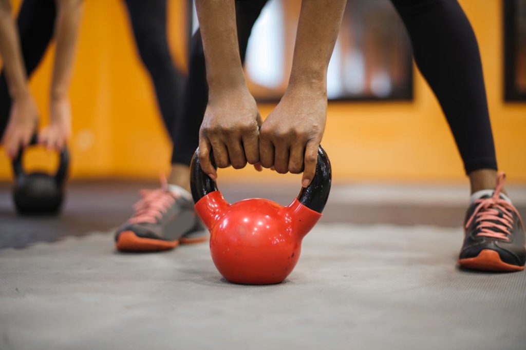 Un sportif tient une kettle bell, les bras tendus vers le sol.