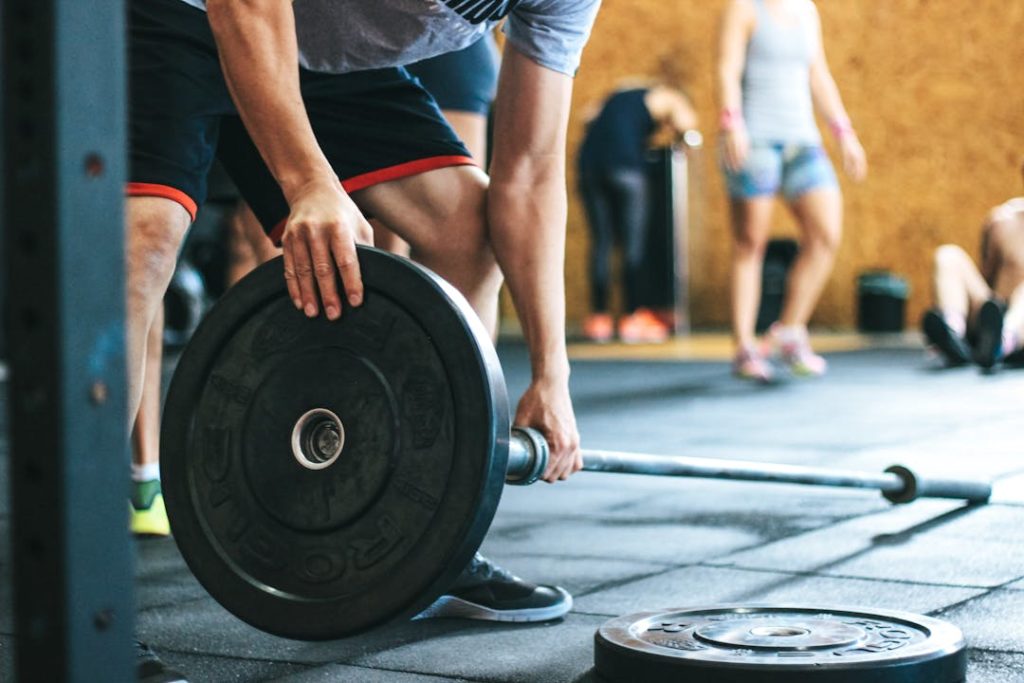 Un sportif installe un disque à une barre dans une salle de sport.