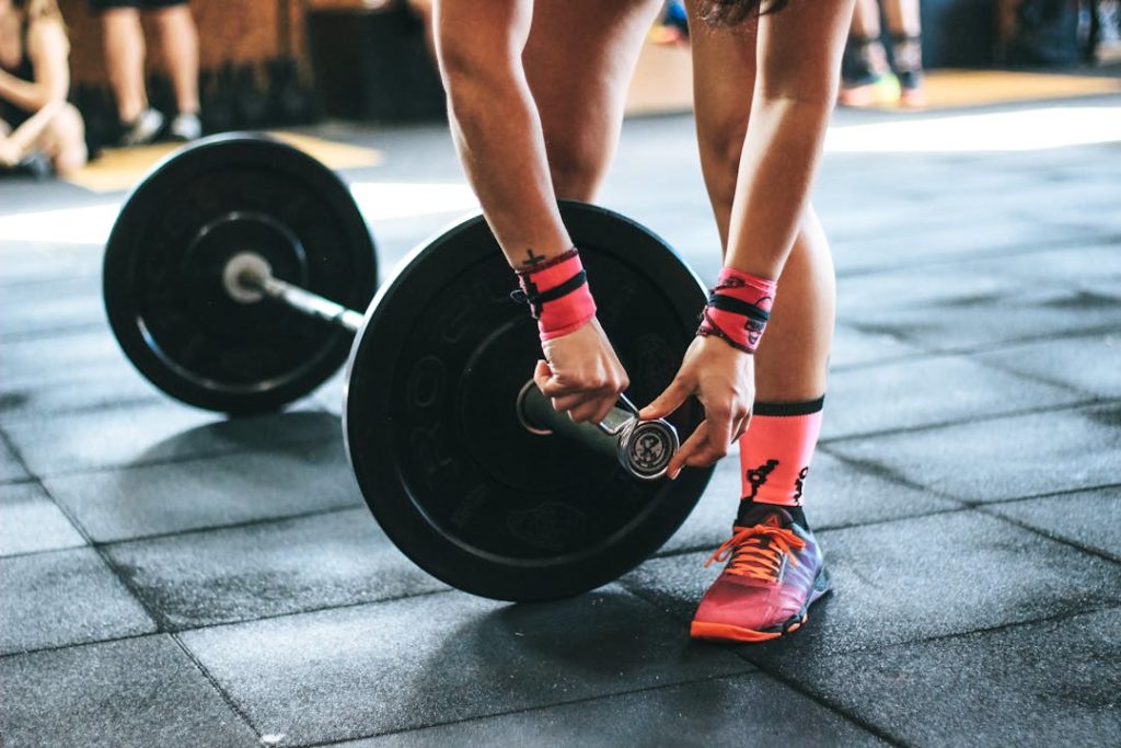 Une sportive est en train d'installer un poids à sa barre.