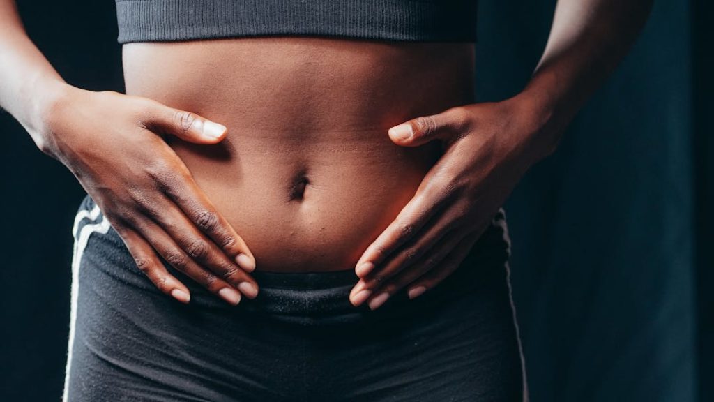 Une femme se tape l'abdomen avec ses deux mains.