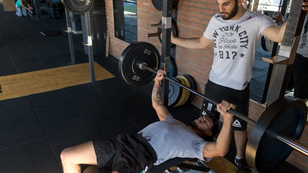 Un prof de sport supervise son client lors d'un entraînement pour se muscler.