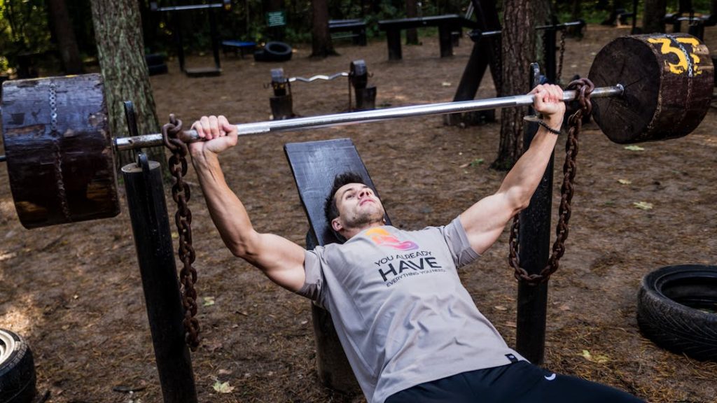Un homme tient une barre sur un banc de musculation à bras tendus, allongé sur le dos.