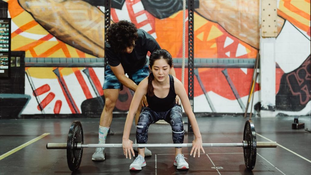 Une femme saisit une barre de cross-training en se faisant guider par son coach.