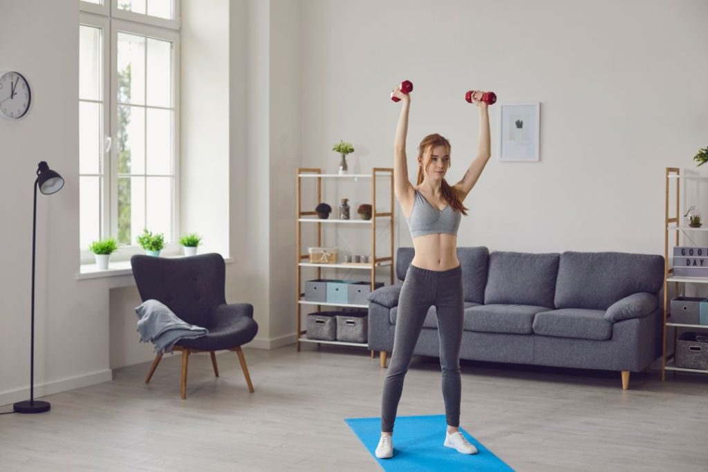 Une jeune femme en train de faire de la musculation chez elle.