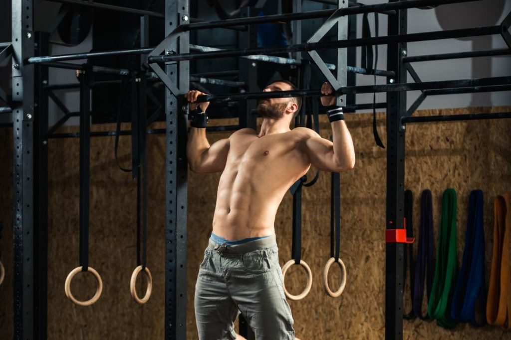 Un homme en train de faire des tractions à la salle de sport.