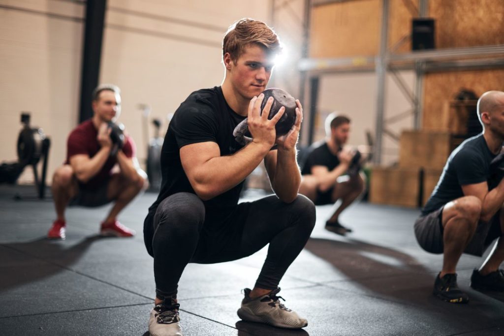 Un sportif est en train de faire des squats dans un box de CrossFit.