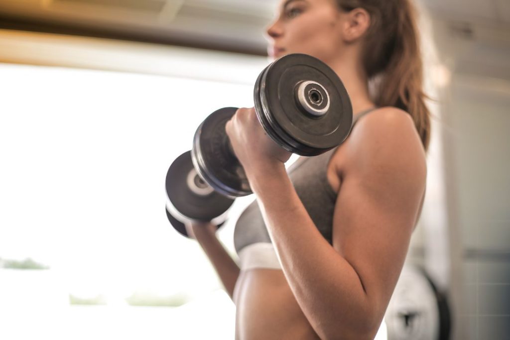 Une femme en train de faire de la musculation avec des haltères.