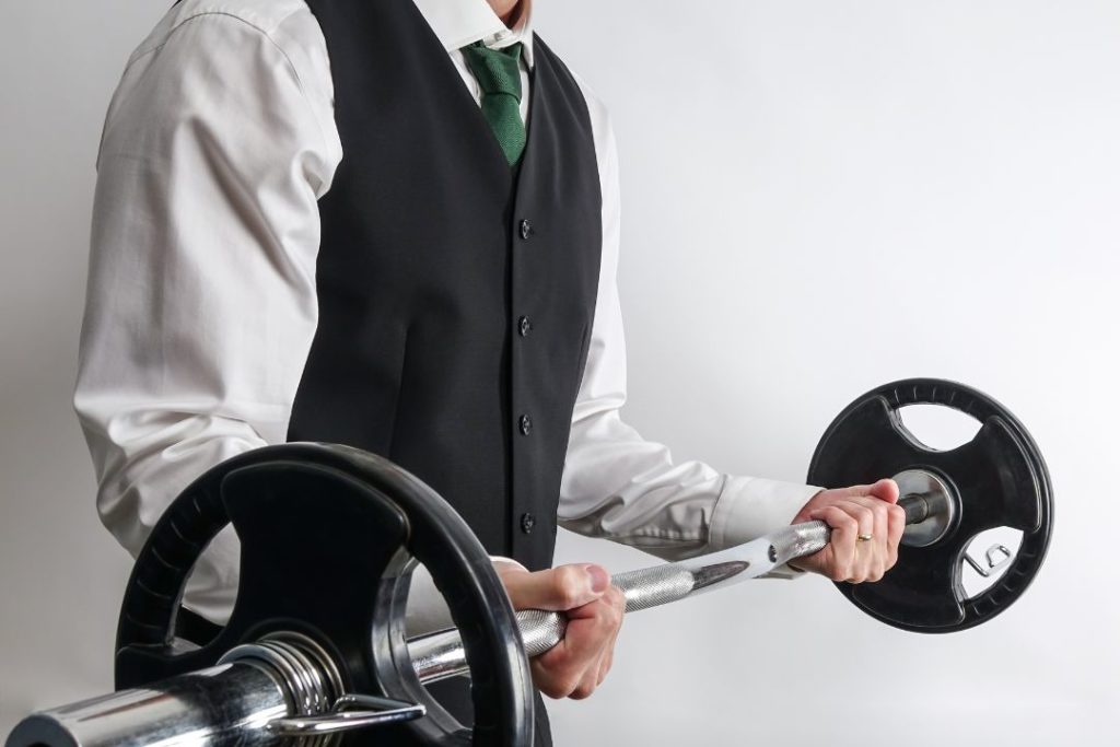 Un homme habillé en tenue professionnelle de bar, tient une barre de musculation.