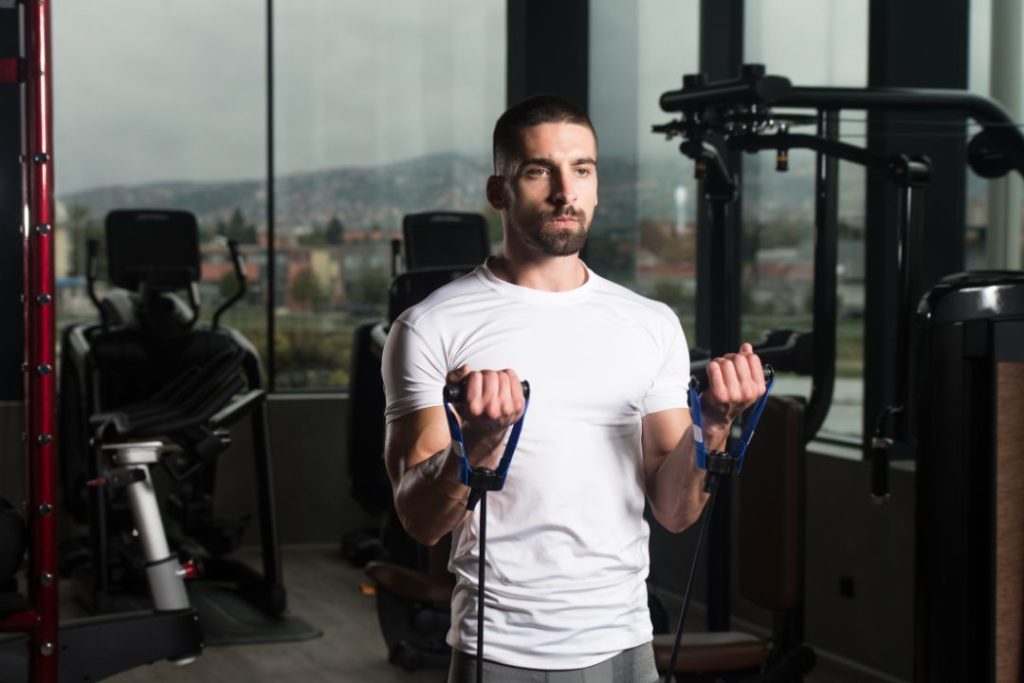 Un jeune homme en train de faire de la musculation en salle de fitness.