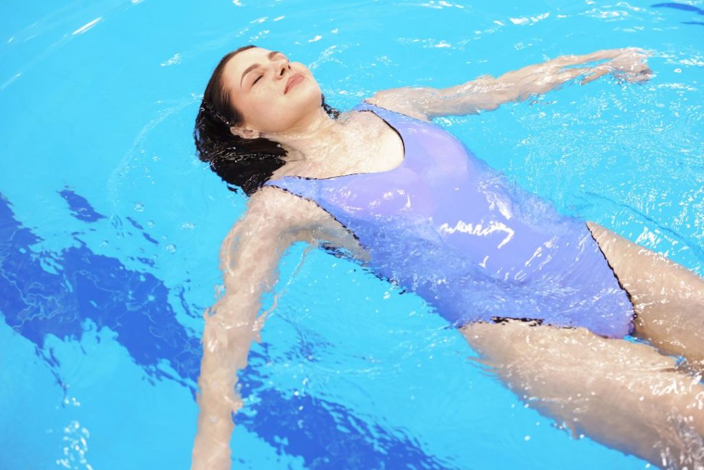 Une femme en train de faire la planche dans la piscine.